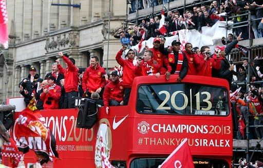Manchester United players cheer from an open-topped bus as they pass the city centre of Manchester, on May 13, 2013